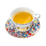 White ceramic teacup and saucer with vibrant floral pattern, filled with golden tea.